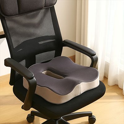 Coussin de siège ergonomique gris en mousse mémoire placé sur une chaise de bureau, apportant un soutien optimal au coccyx et réduisant la pression sur le bas du dos.