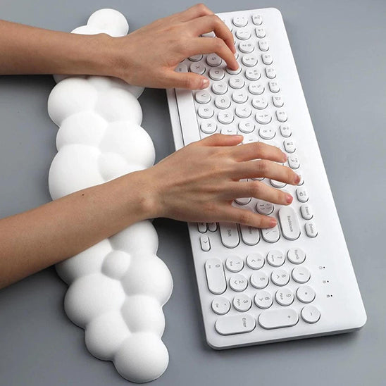 Mains sur un clavier avec un repose-poignet blanc en forme de nuage, vu de dessus.