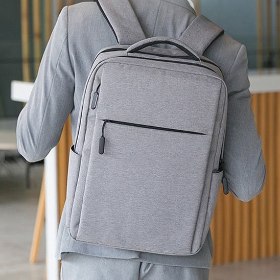 Homme d’affaires portant un sac à dos ordinateur gris clair, idéal pour le travail, les rendez-vous professionnels et les trajets quotidiens.