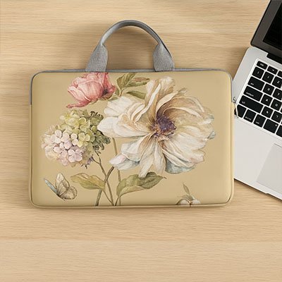 Sacoche ordinateur femme beige au design floral délicat, posée à côté d’un laptop argenté.