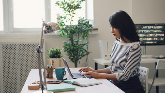 Femme en télétravail assise droite à son bureau devant un ordinateur portable