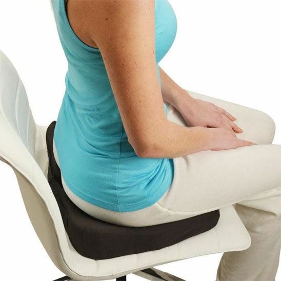 Femme assise sur un coussin mémoire de forme noir dans une ambiance zen.