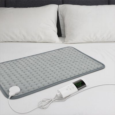 Coussin chauffant ThermaRelief avec télécommande et écran LED sur lit blanc