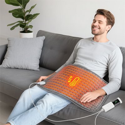 Homme détendu avec le coussin chauffant électrique ThermaRelief sur le ventre