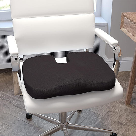 Coussin noir sur une chaise blanche moderne avec décor minimal.