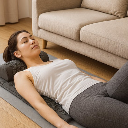 Femme allongée sur un tapis d’acupression gris, profitant d’un moment de relaxation pour soulager les tensions du dos.