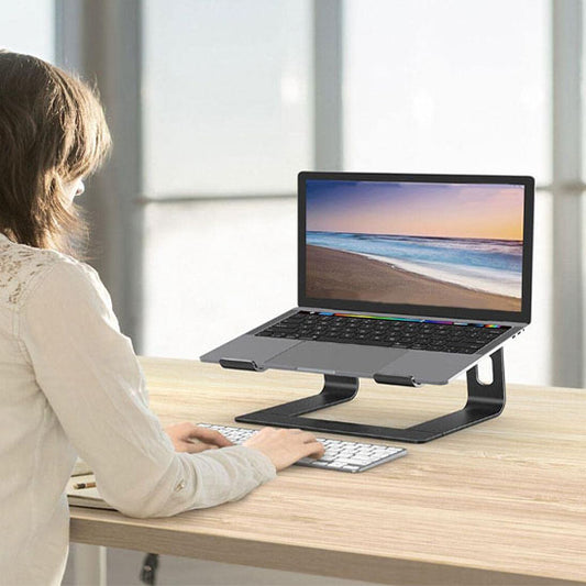 Femme tapant sur clavier avec écran surélevé par un support ordinateur portable ergonomique en aluminium dans un bureau lumineux