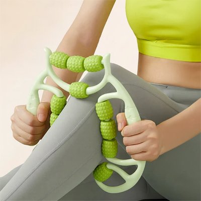 Une femme utilise un rouleau de massage vert sur ses jambes pour soulager les tensions musculaires et améliorer la circulation après une longue journée de travail.