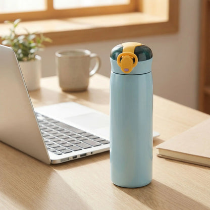 Gourde isotherme bleue 460 ml avec bouchon à paille intégrée posée sur un bureau près d’un ordinateur