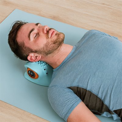 Homme allongé sur un tapis utilisant un masseur cervical ergonomique pour soulager les tensions de la nuque.