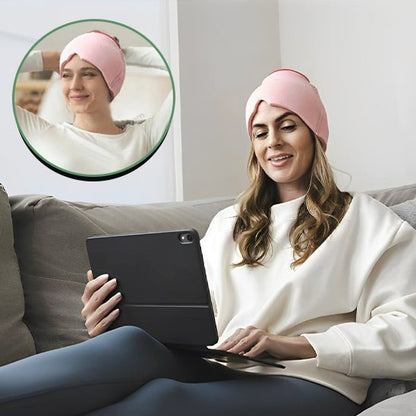 Femme détendue sur un canapé, portant le bonnet relaxant SereniCap™ rose en lisant sur sa tablette
