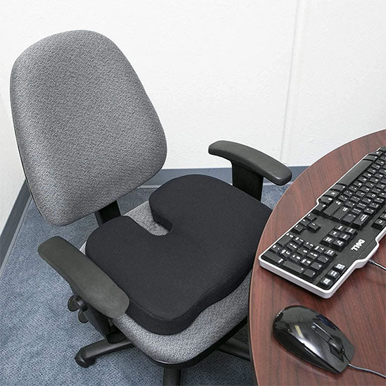 Coussin ergonomique en forme de U posé sur une chaise de bureau, vue rapprochée.