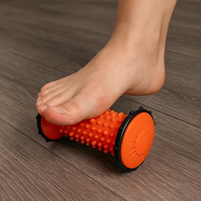 Rouleau de massage orange utilisé sous la voûte plantaire pour soulager les tensions et améliorer la circulation sanguine.