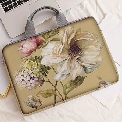 Élégante sacoche ordinateur femme à motif floral beige, posée près d’un ordinateur portable.