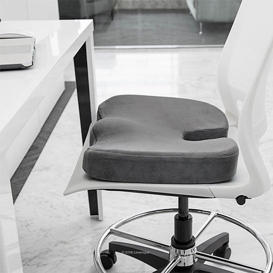 Coussin gris sur chaise design, indiqué pour soulager les douleurs de dos.