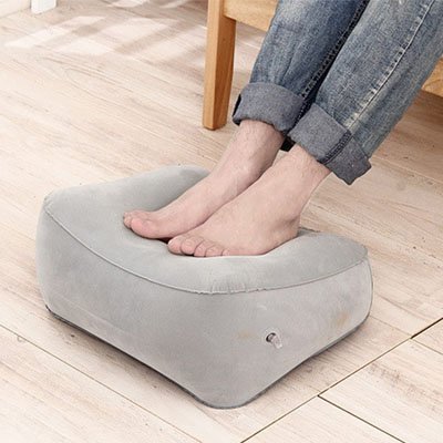 Personne posant ses pieds nus sur un repose-pieds de bureau ergonomique gris pour soulager la fatigue.