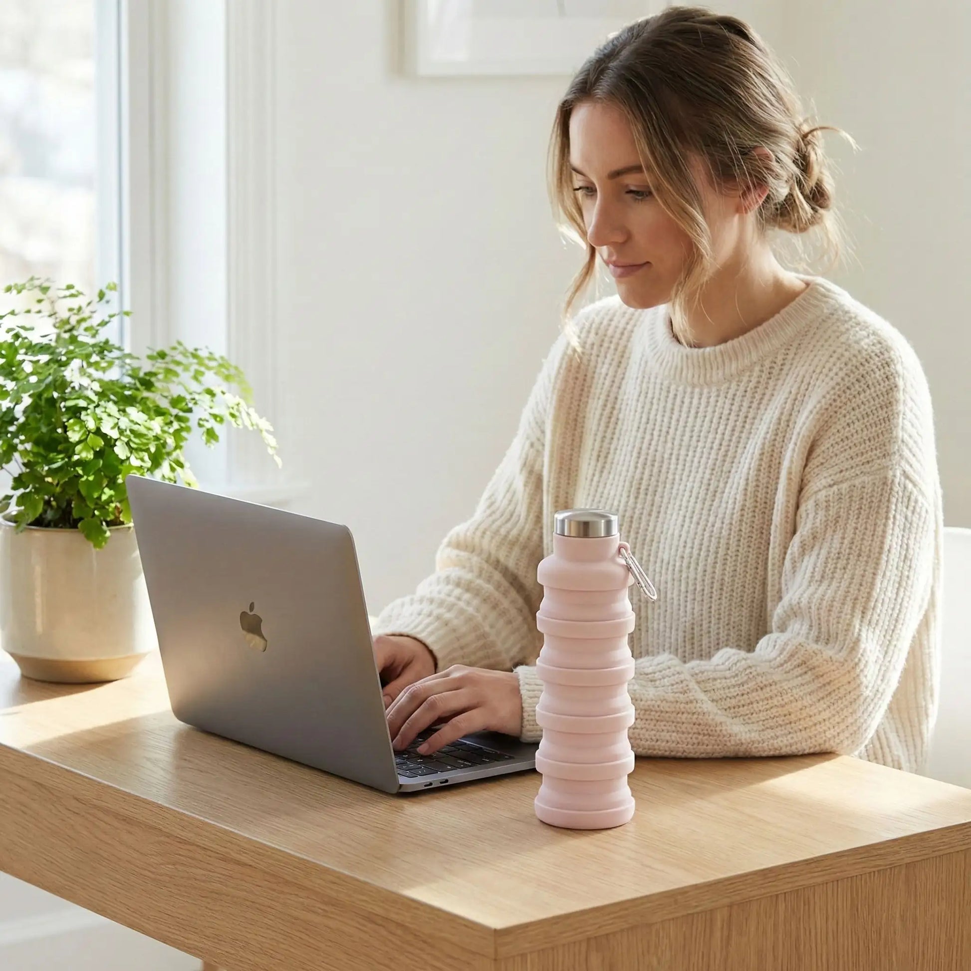 Femme en télétravail utilisant une gourde de sport pliable rétractable rose