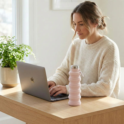 Femme en télétravail utilisant une gourde de sport pliable rétractable rose