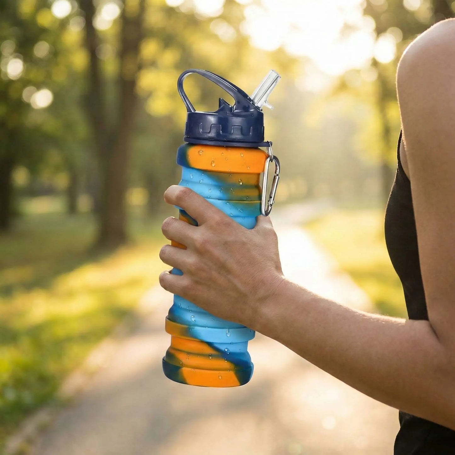 main tenant une gourde de sport pliable en silicone pendant activité extérieure