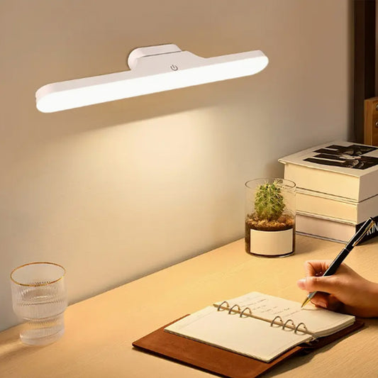 Lampe LED murale éclairant un bureau avec un carnet ouvert et une main en train d’écrire