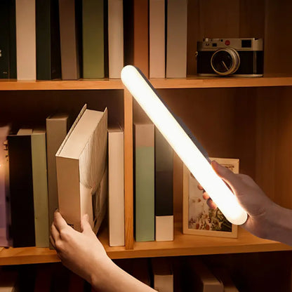 Lampe LED tenue à la main devant une bibliothèque pour éclairer les livres