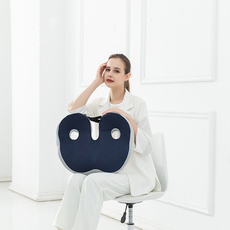 Femme assise sur une chaise tenant un coussin ergonomique de siège bleu pour montrer sa praticité et sa portabilité.
